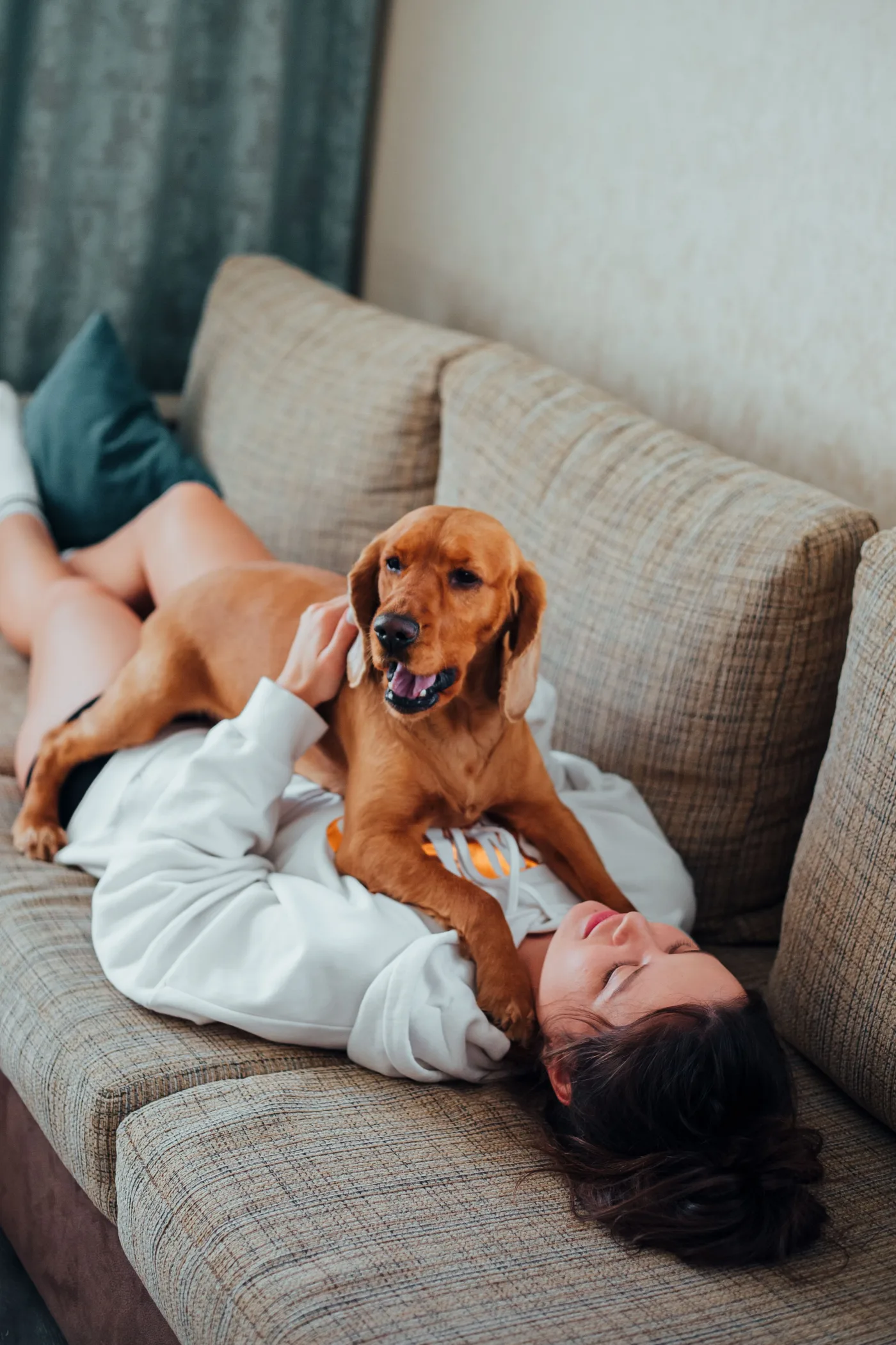 Una mujer descansando en el sofá abrazada a su perro